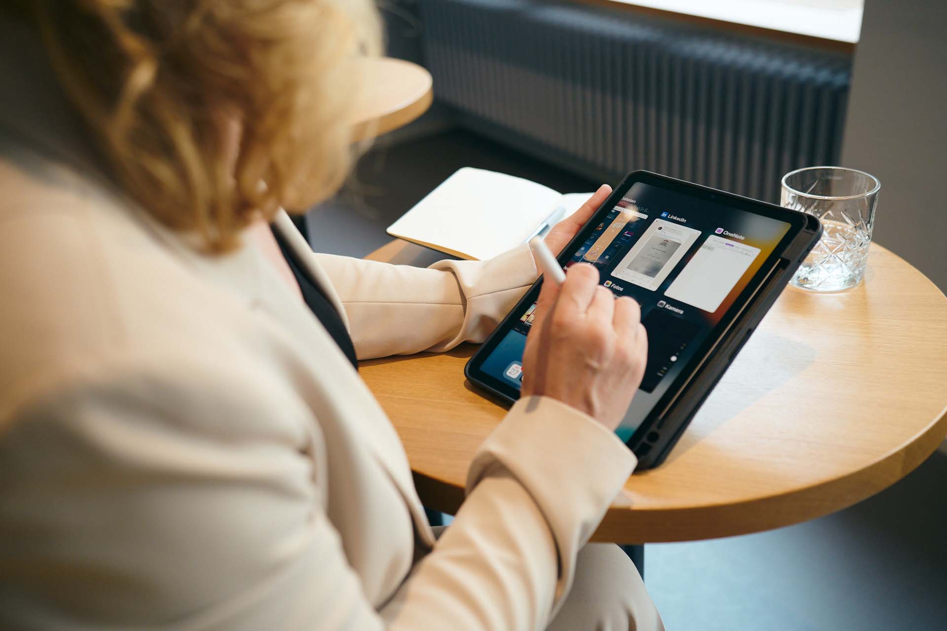 Elisabeth sitzt in der Lobby im Hotel Alma und arbeitet konzentriert auf ihrem Tablet.