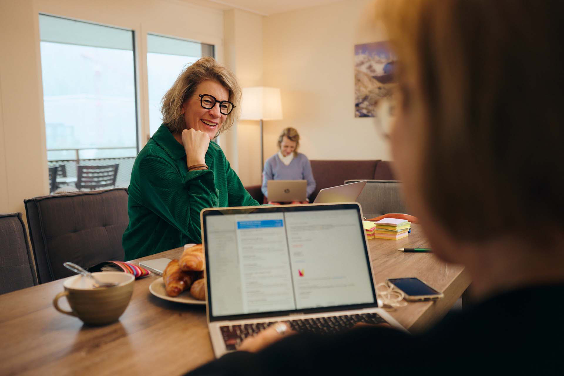 Nicoletta, Isabelle und Karin sind im Peaks Place für Workation. Gearbeitet wird am Esszimmertisch. Nicoletta und Isabelle tauschen sich aktiv aus.