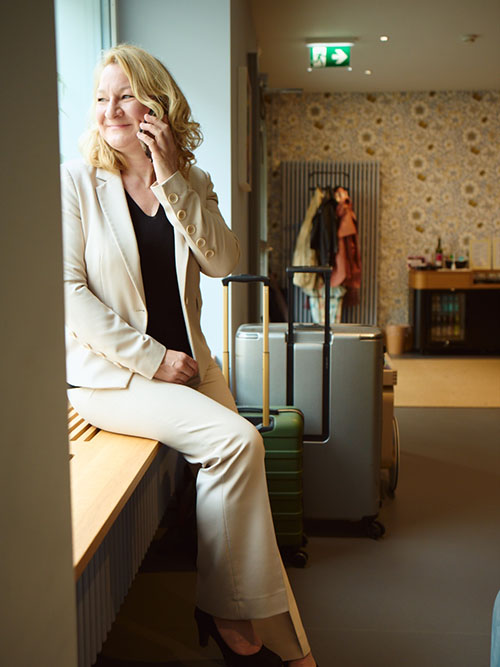 Elisabeth entspannt telefonierend und auf den Check-In wartend in der Lobby des Hotel Alma. 